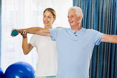 Physical therapist working with patient with hand weights